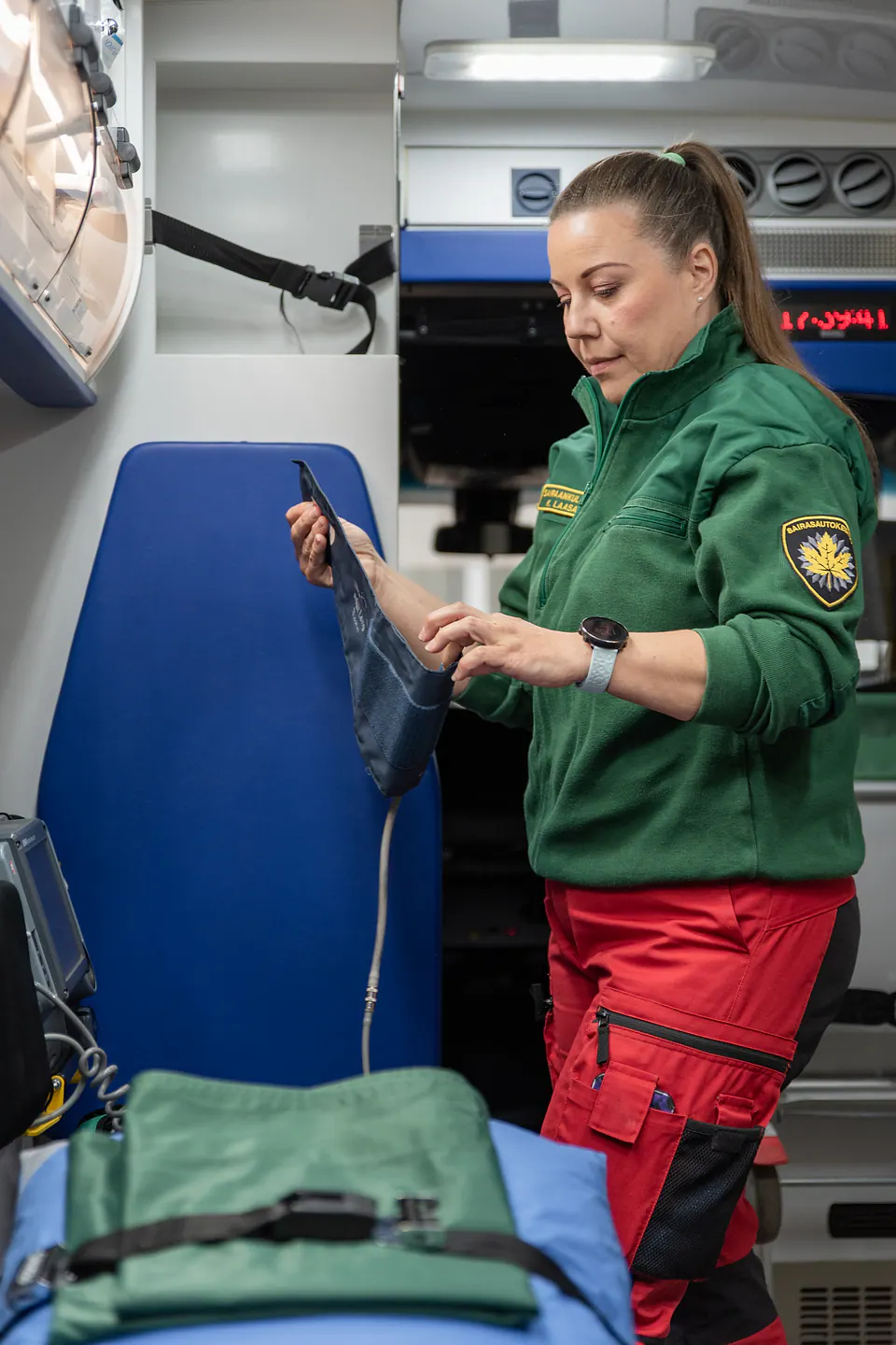 Yksityiskohdat tarkastuksessa Työntekijä tarkastelee sinistä varustetta ambulanssin valaistussa takaosassa.
