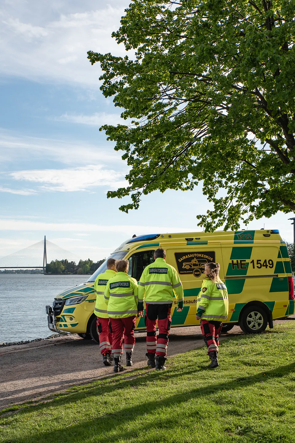 Yhdessä autolle Neljä työntekijää lähestyy ambulanssia rantareitillä, ja yksi heistä katsoo sivulle ryhmää kohti.