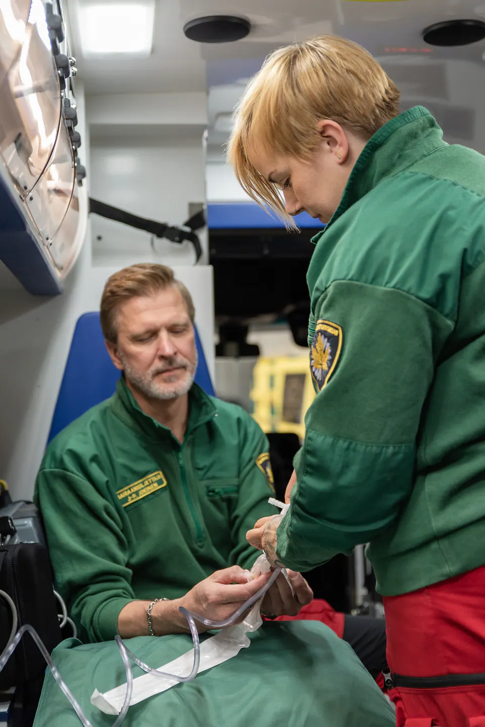 Keskittynyt työpari Kaksi työntekijää kokoaa läpinäkyvää letkua ambulanssin takaosassa.